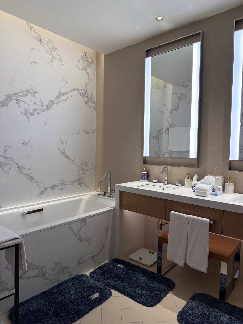 Modern bathroom with a minimalist design. The walls are covered in a white marble-like wallpaper with a subtle texture. On