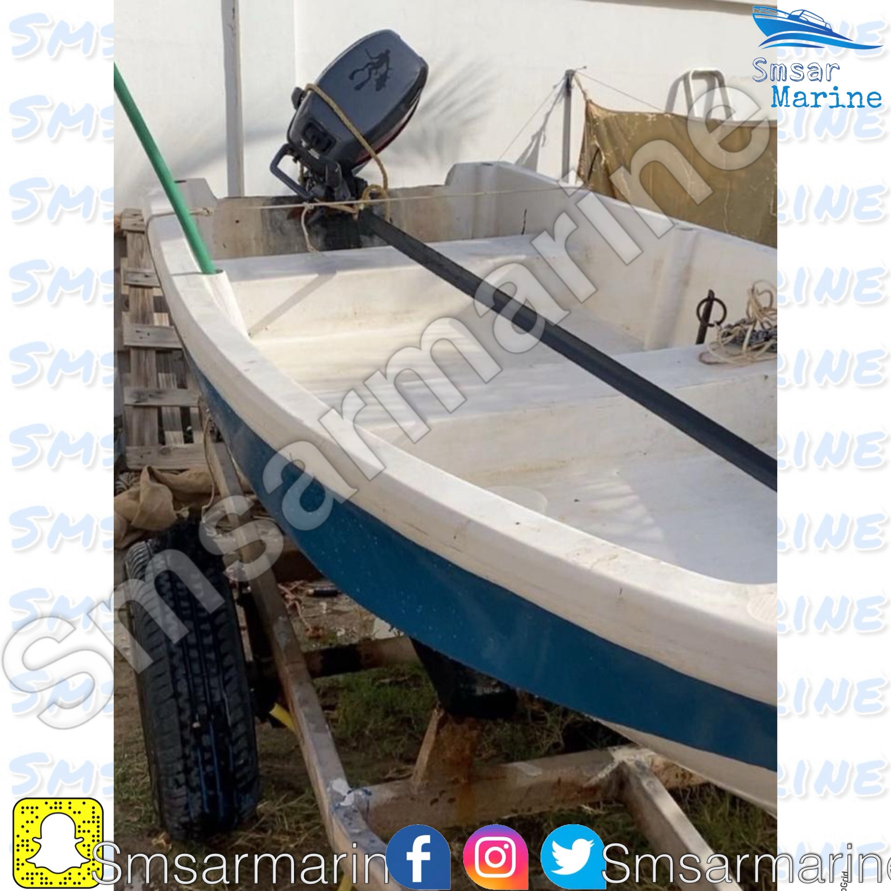 Small boat on a trailer. The boat is white with blue stripes on the sides and a black motor on the back. The trailer is made