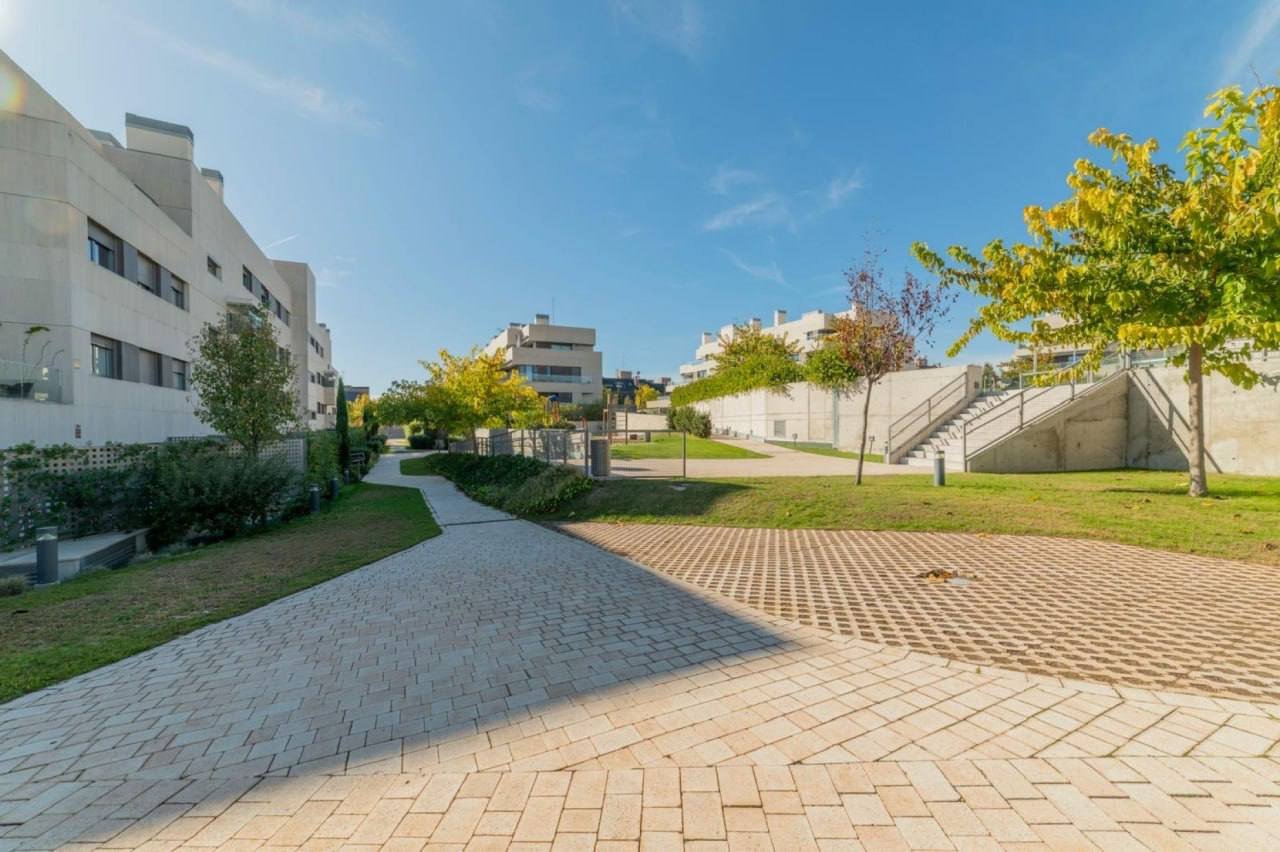 Beautiful landscape of a residential area with a clear blue sky. In the foreground, there is a paved walkway made of red