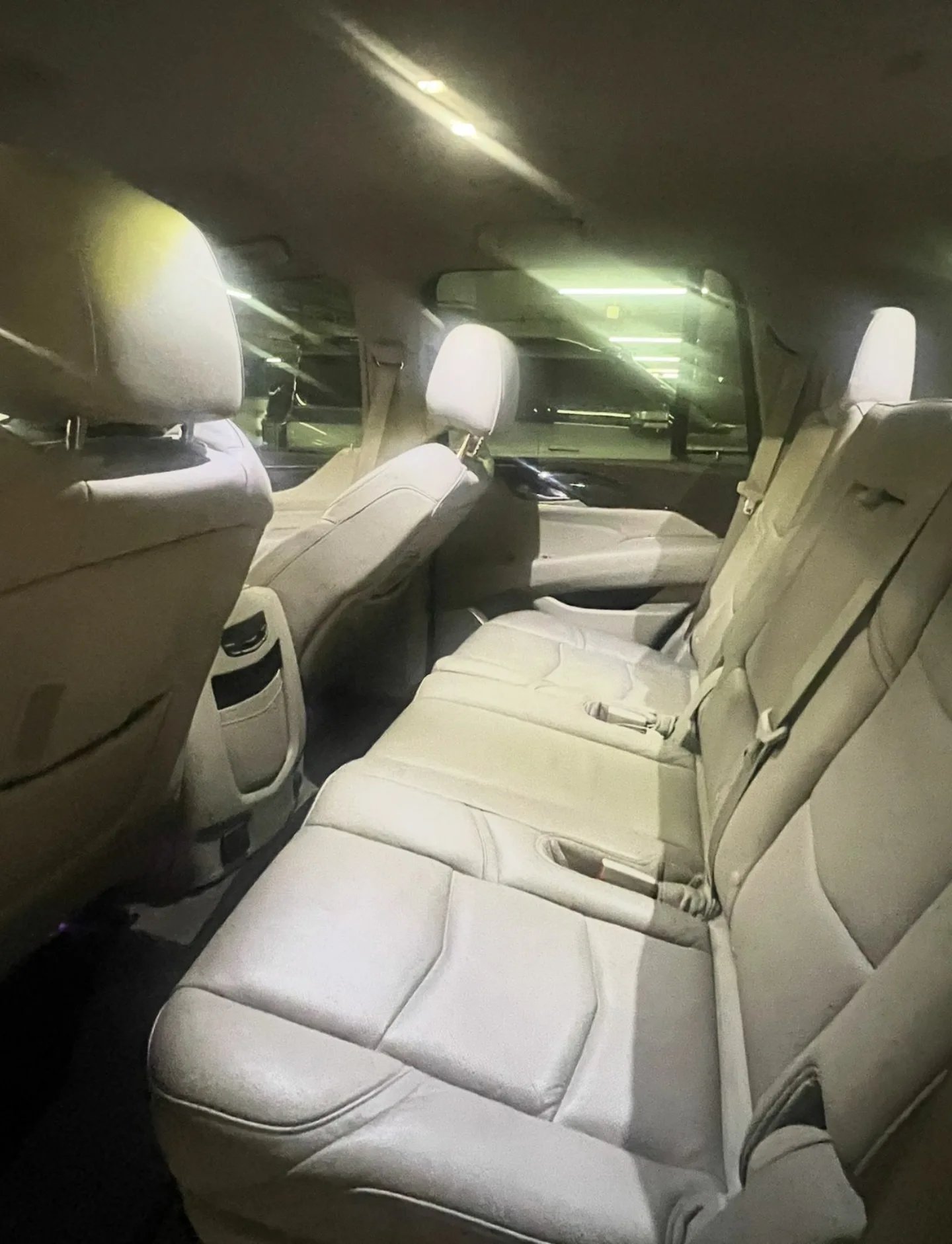 Interior of a car, specifically the back seats. The seats are beige in color and appear to be made of leather. The back