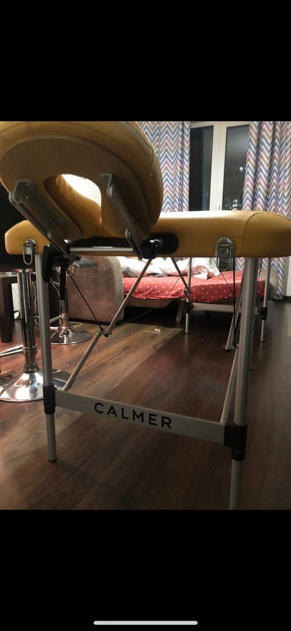 Yellow massage table with the word "CALMER" written on it. The table is made of metal and has a curved backrest and