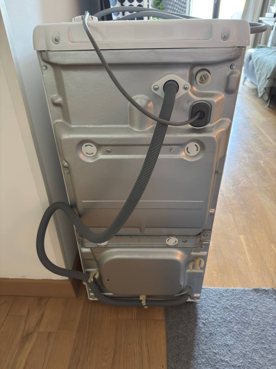 Close-up of the back panel of a washing machine. The panel is made of metal and has a rectangular shape with rounded edges.