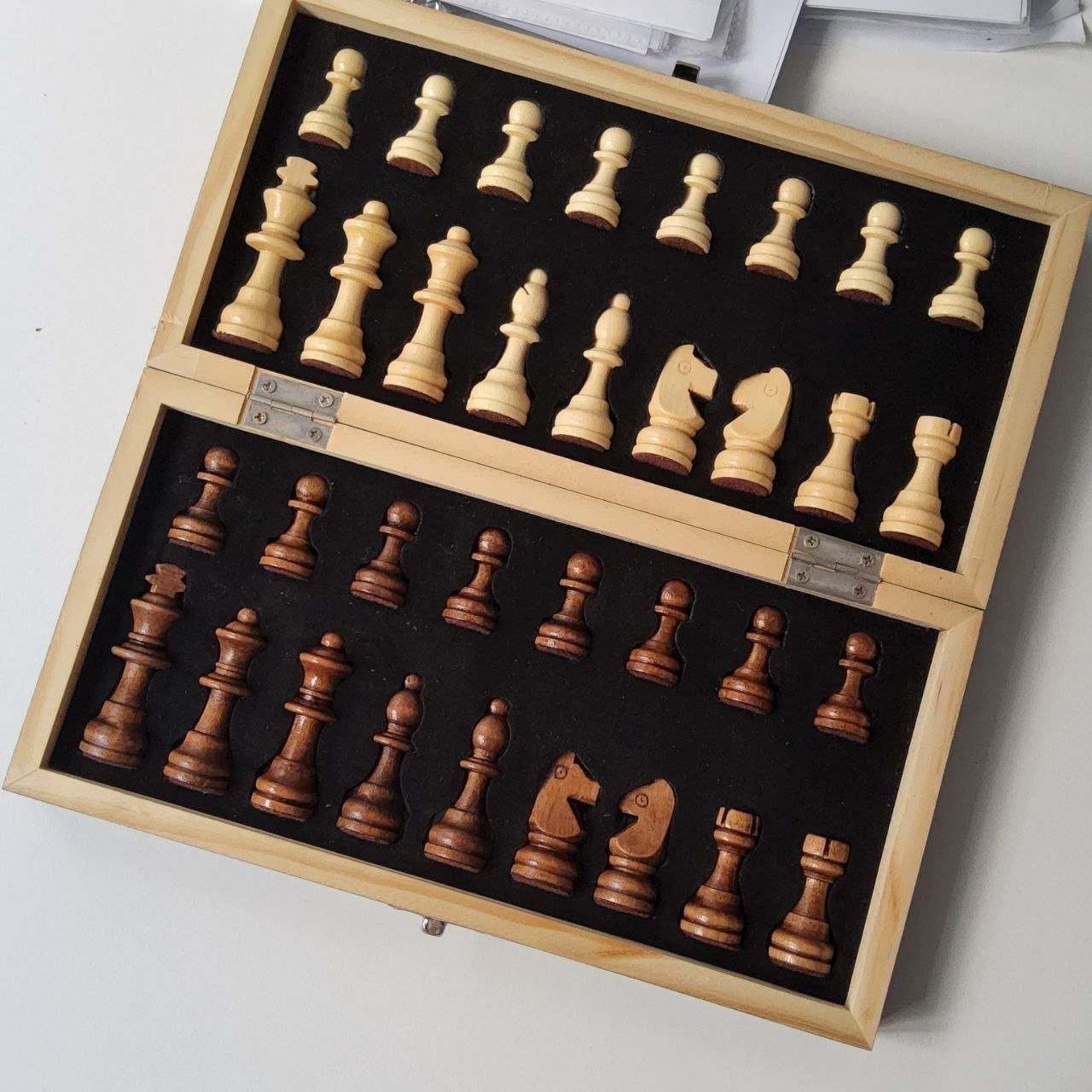 Wooden chess set in a wooden box. The box is rectangular in shape and has a lid that can be opened to reveal the chess