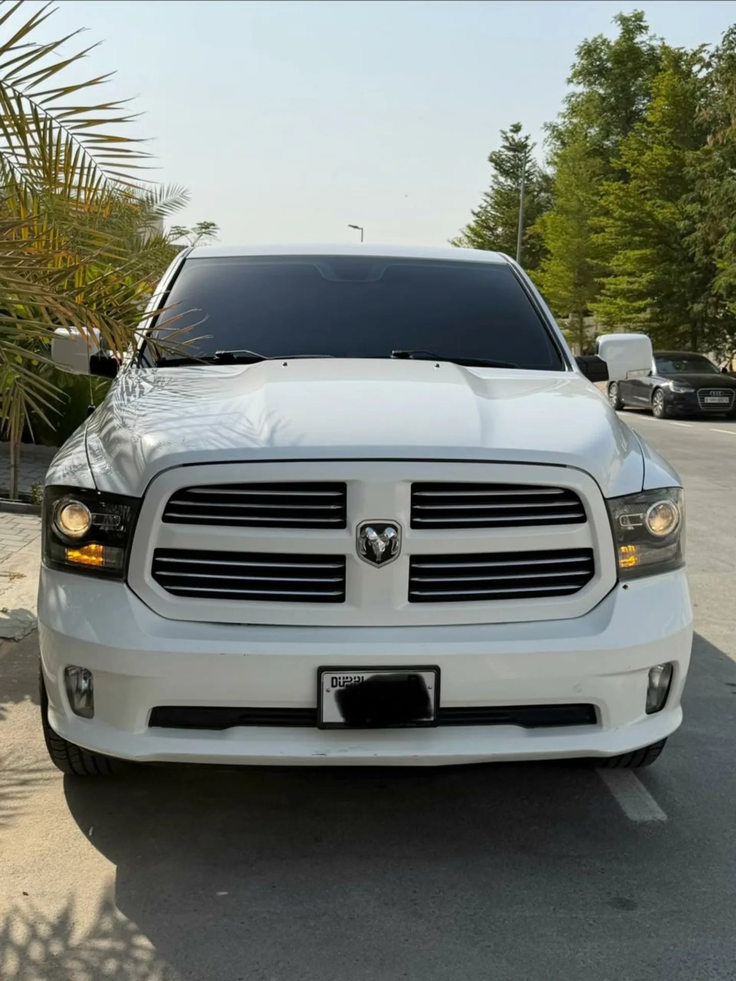 White Dodge Ram truck parked in a parking lot. The truck is facing towards the left side of the image and is positioned in