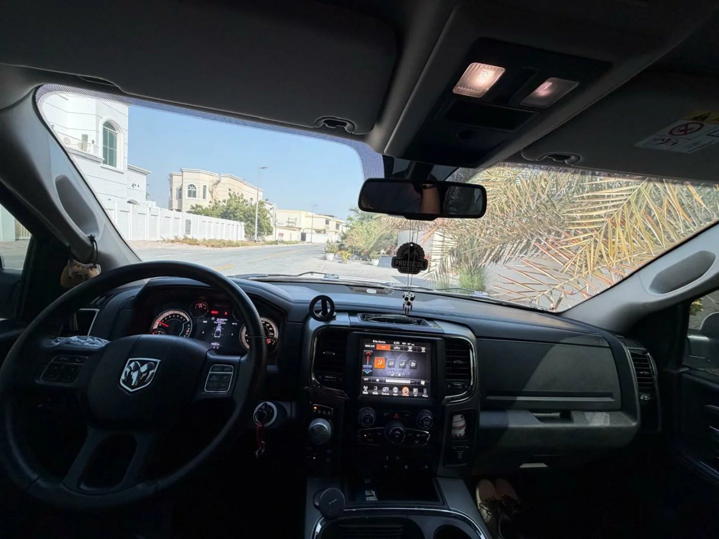 Interior of a car, specifically the driver's seat and dashboard. The car appears to be a Dodge Ram, as indicated by the logo