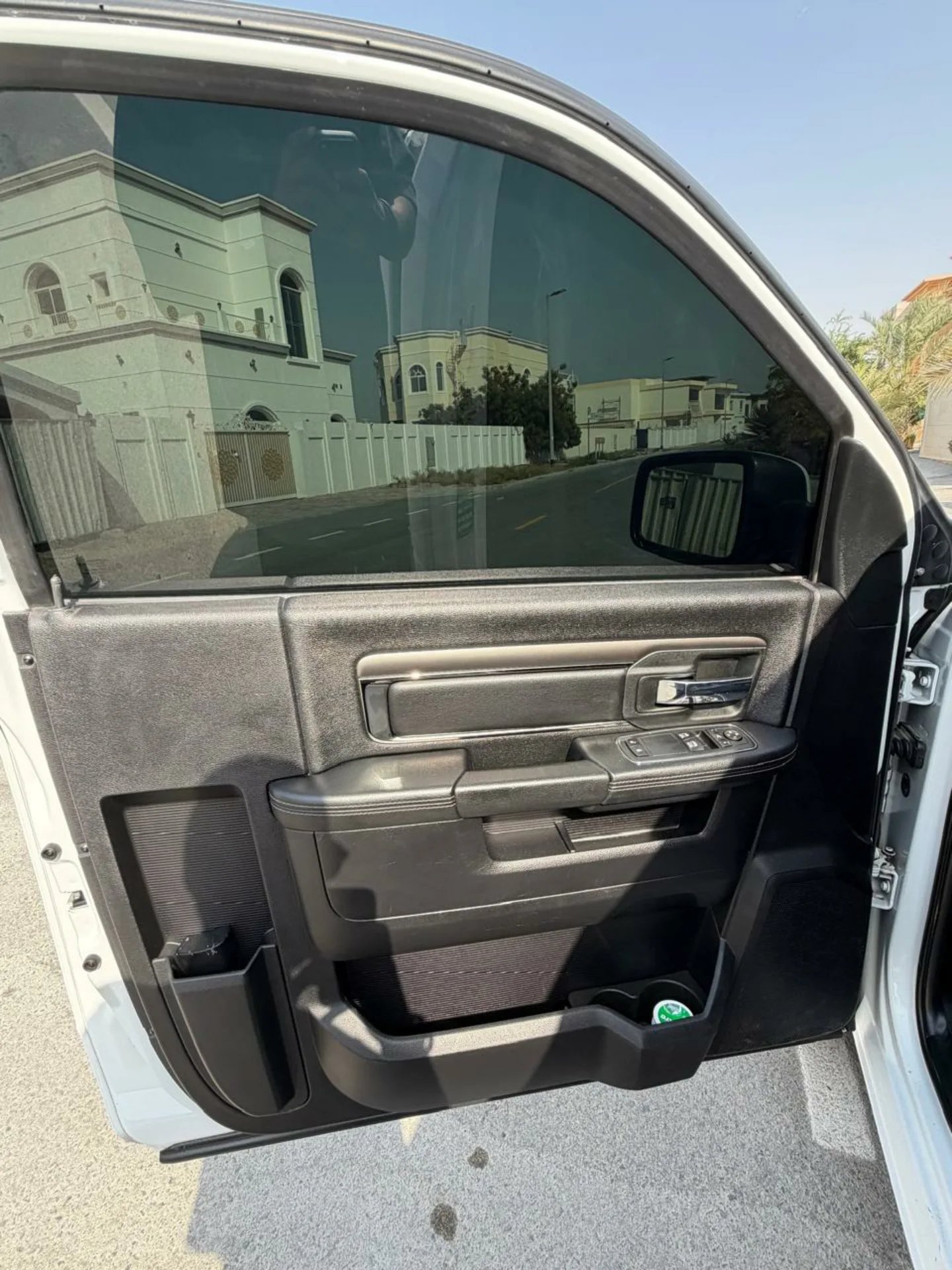 Interior of a car with the door open. The door panel is black and appears to be made of plastic. The handle is silver and