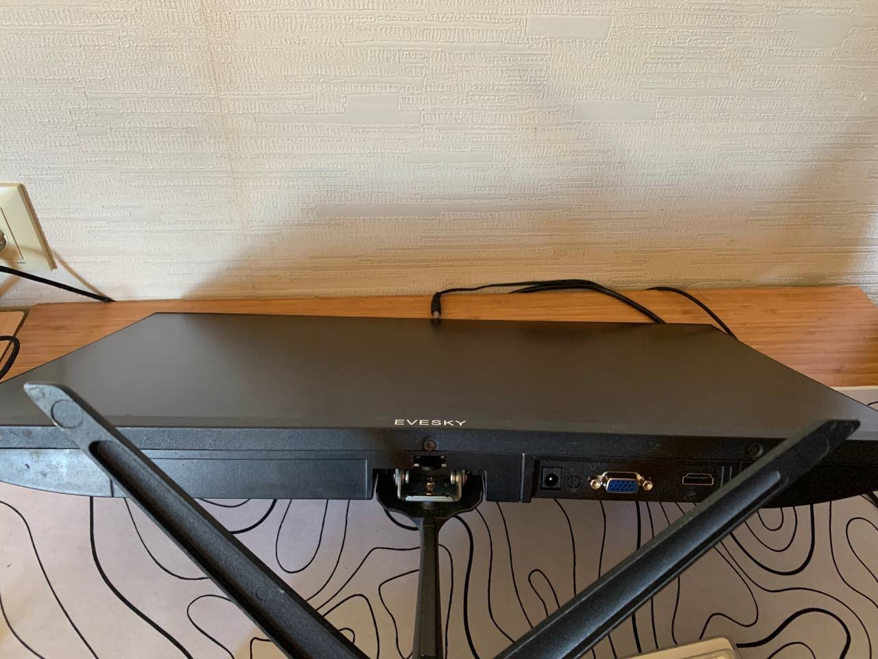 Black electronic device, possibly a TV, sitting on top of a wooden desk. The device has a USB port on the right side and a