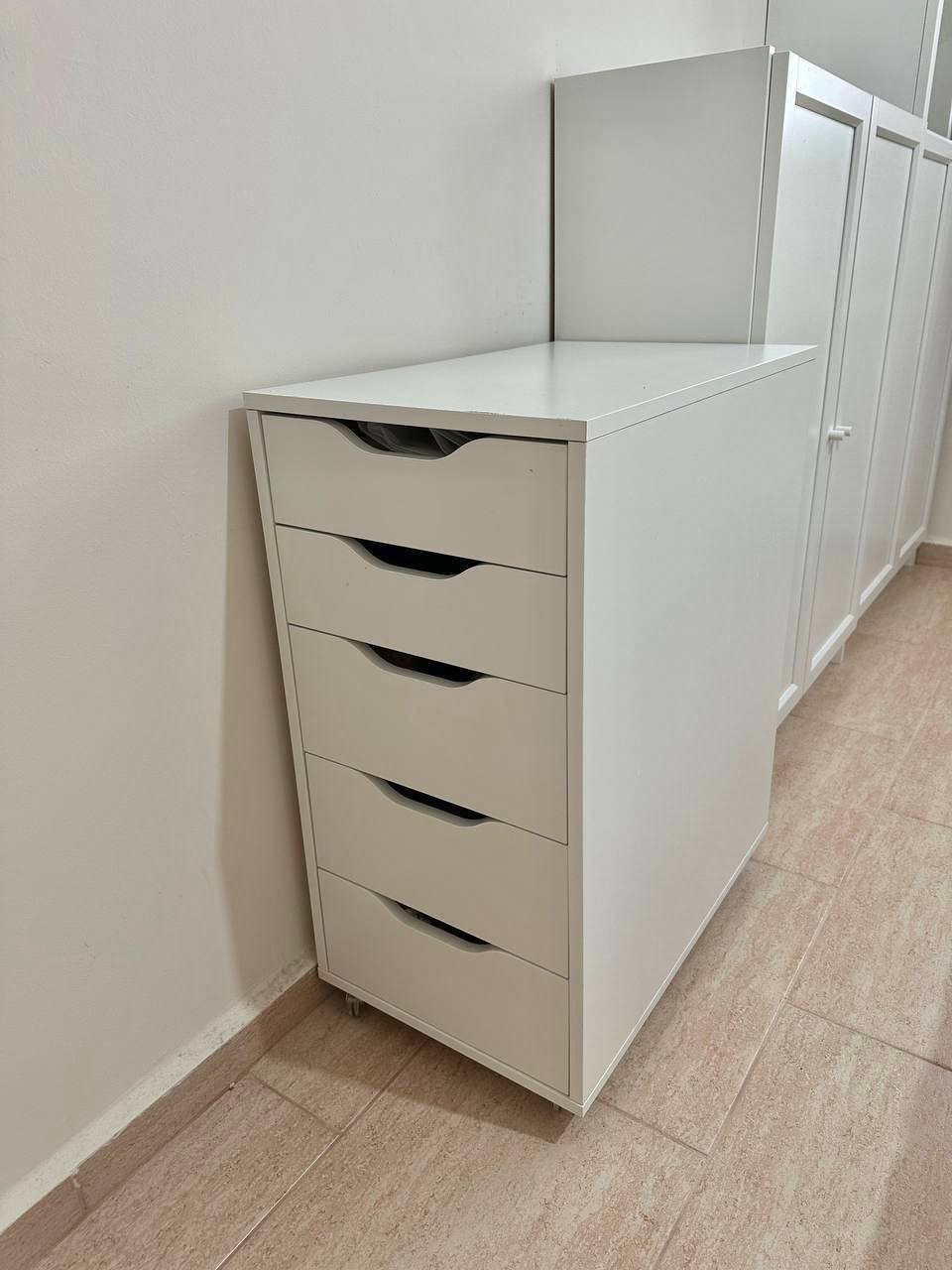 White filing cabinet with six drawers in a room with beige tiles flooring. The filing cabinet is tall and rectangular in