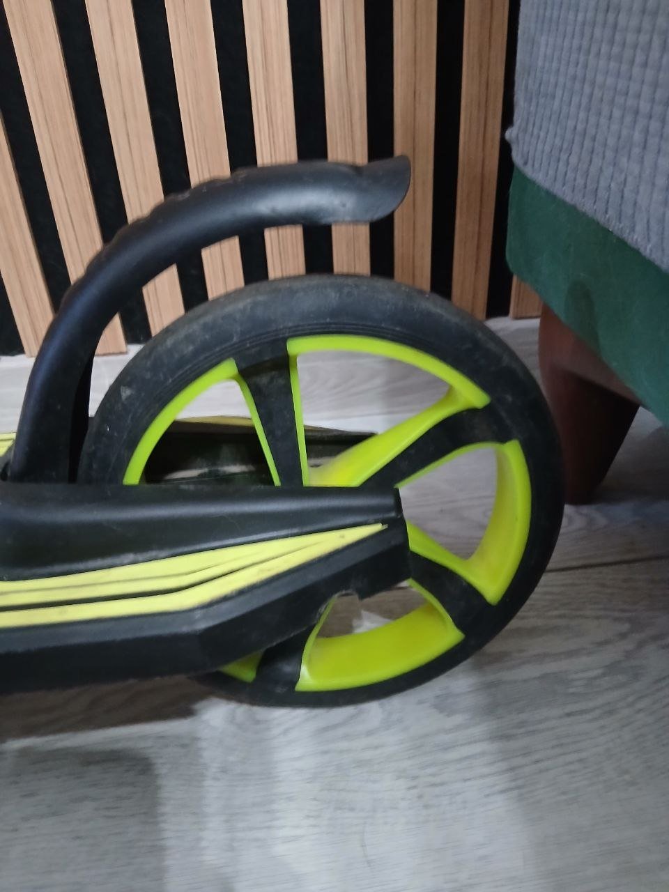 Close-up of a black and yellow wheel with a black handle. The wheel appears to be made of plastic and has a curved shape