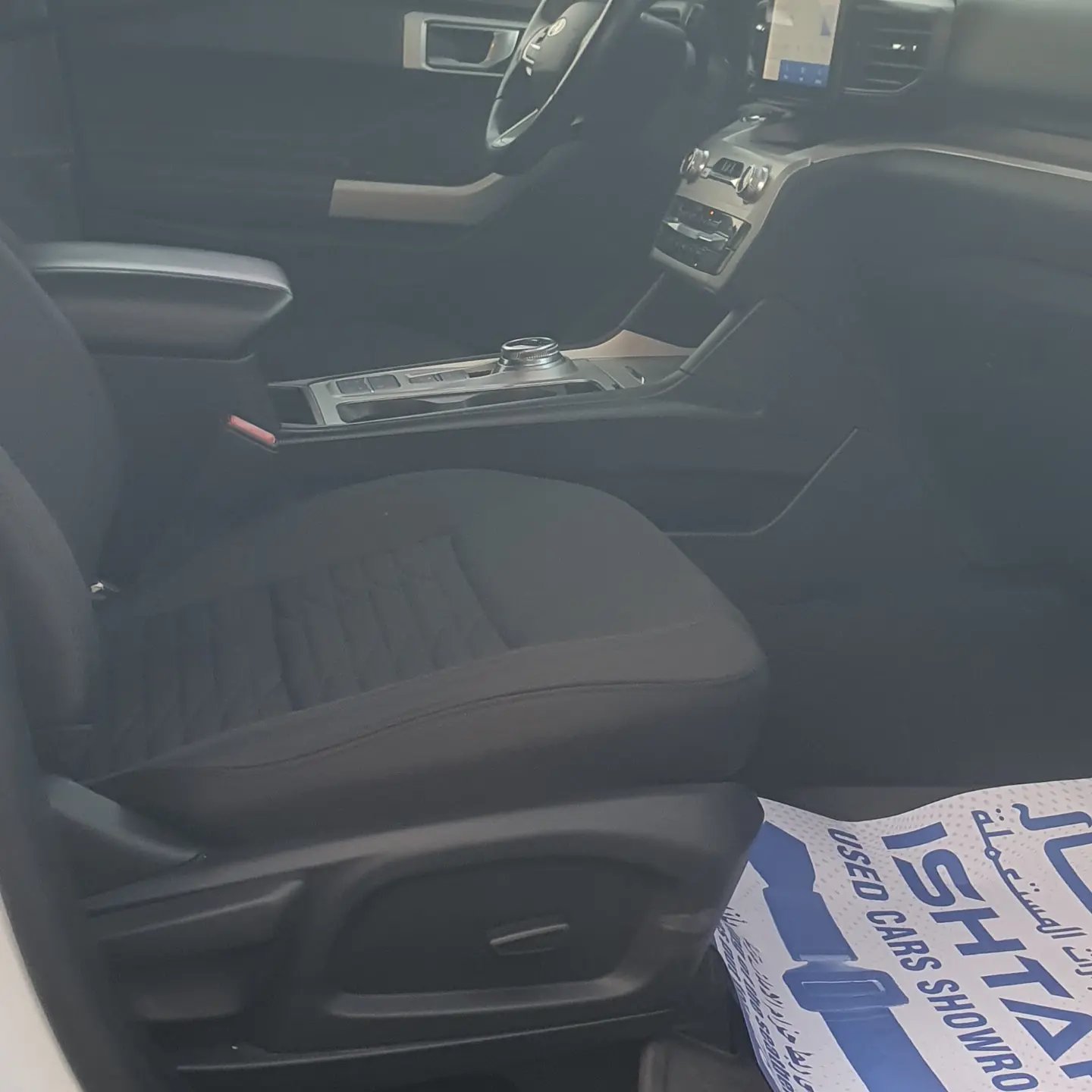 Interior of a car, specifically the driver's seat. The seat is black and appears to be made of leather. The dashboard is
