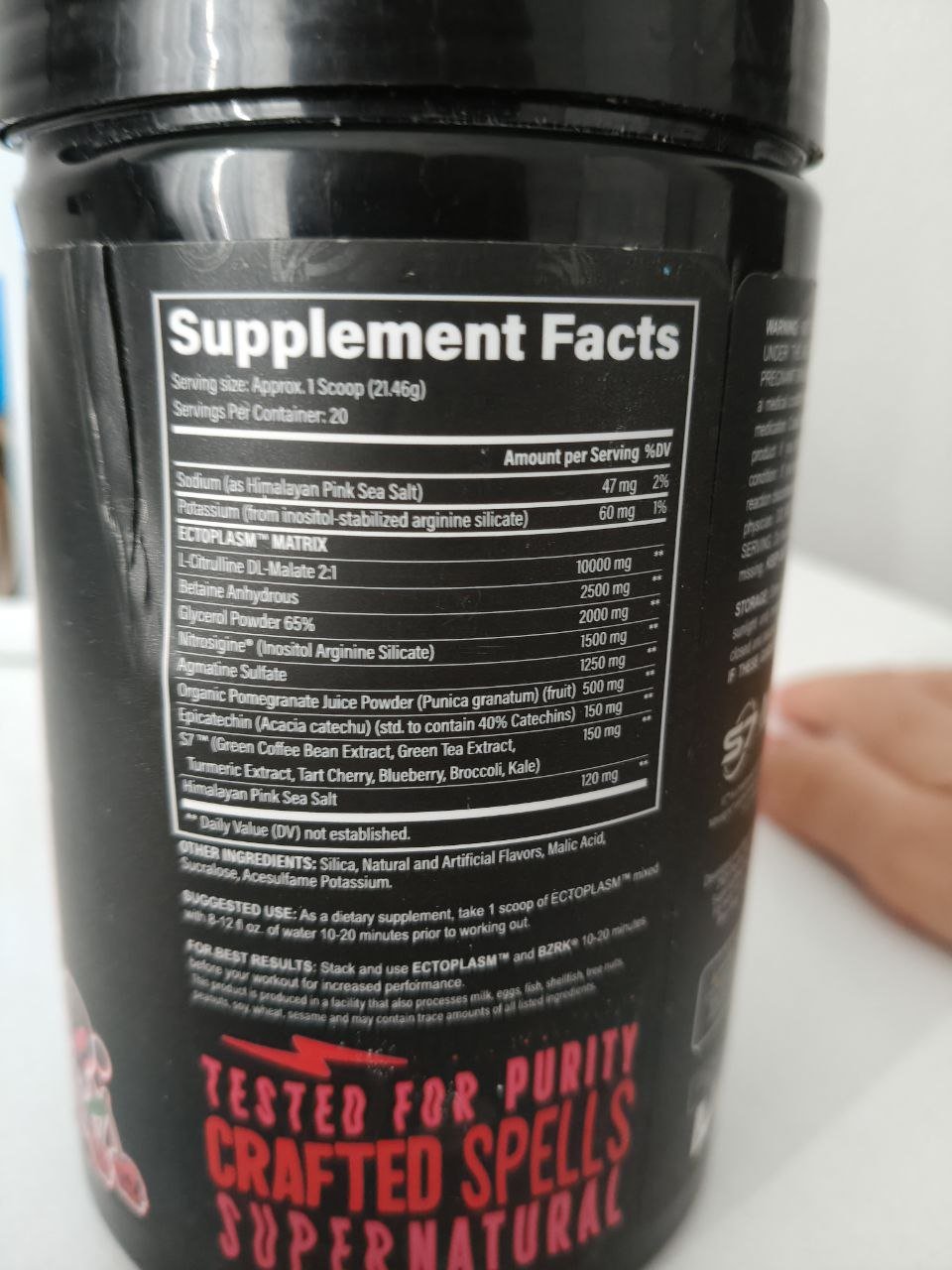 Close-up of a black plastic container with a label on it. The label has white text that reads "Supplement Facts" and "Tested