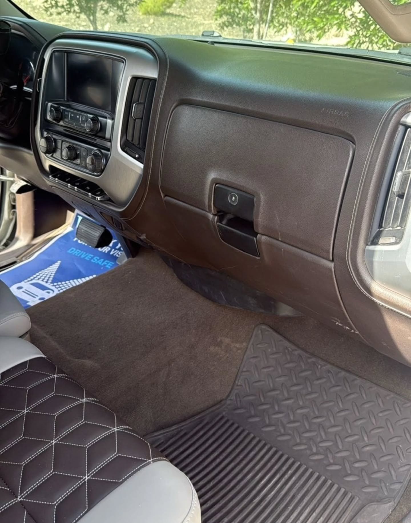 Interior of a car, specifically the driver's seat and the dashboard. The dashboard is black and has a large touch screen