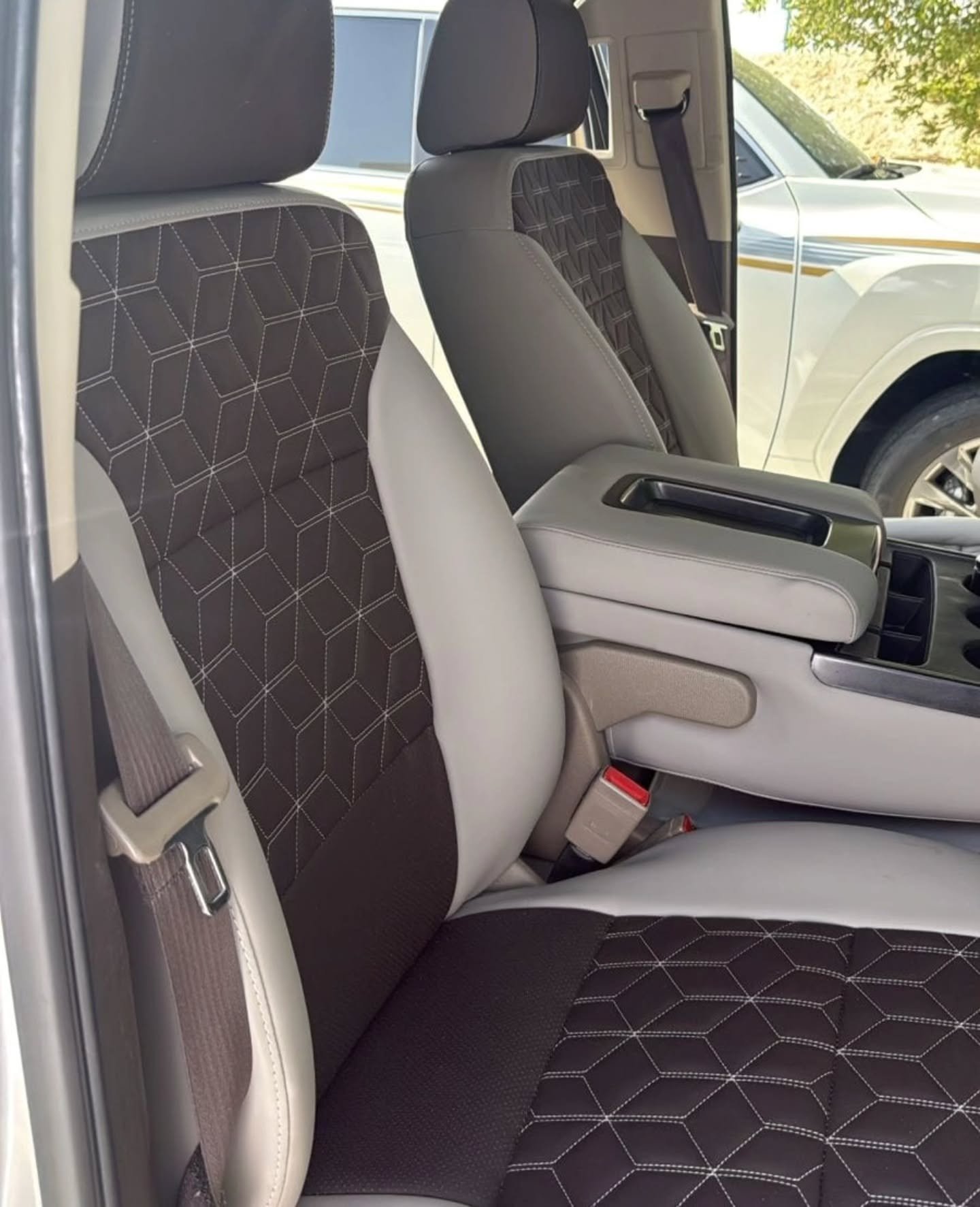 Interior of a car, specifically the front seats. The seats are upholstered in a dark grey fabric with a geometric pattern.