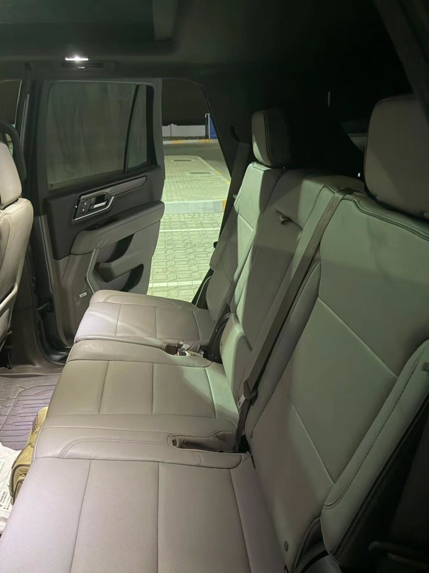 Interior of a car, specifically the back seat of a pickup truck. The seats are beige in color and appear to be made of
