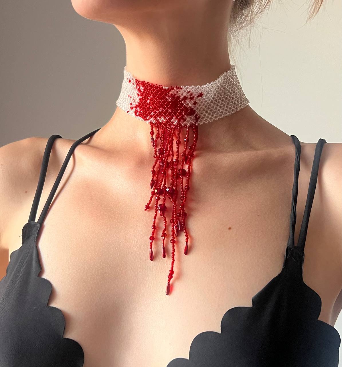 Close-up of a woman's neck and upper body. She is wearing a black halter top with a white lace collar. The collar is made up