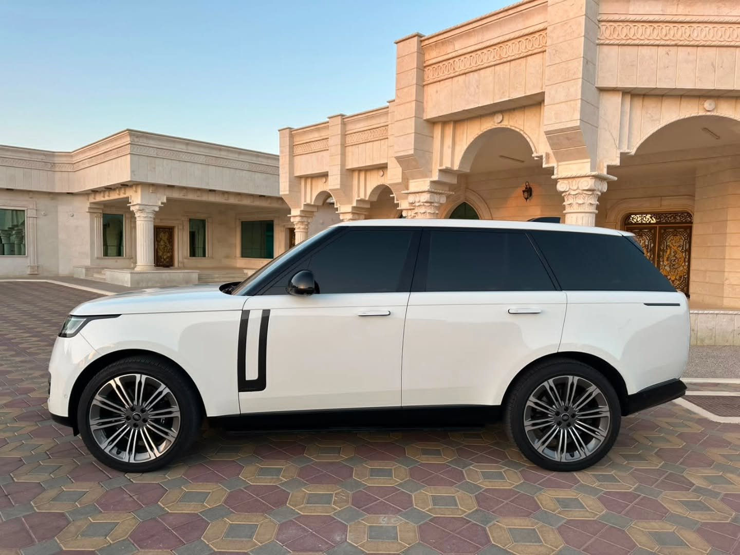 White Range Rover parked in front of a luxurious building. The building appears to be a palace or palace with ornate