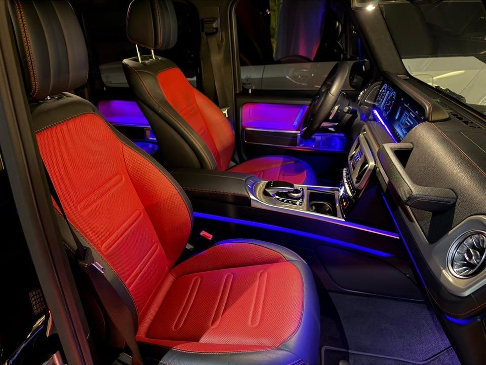 Interior of a car, specifically the front seats. The seats are upholstered in red leather with black stitching. The