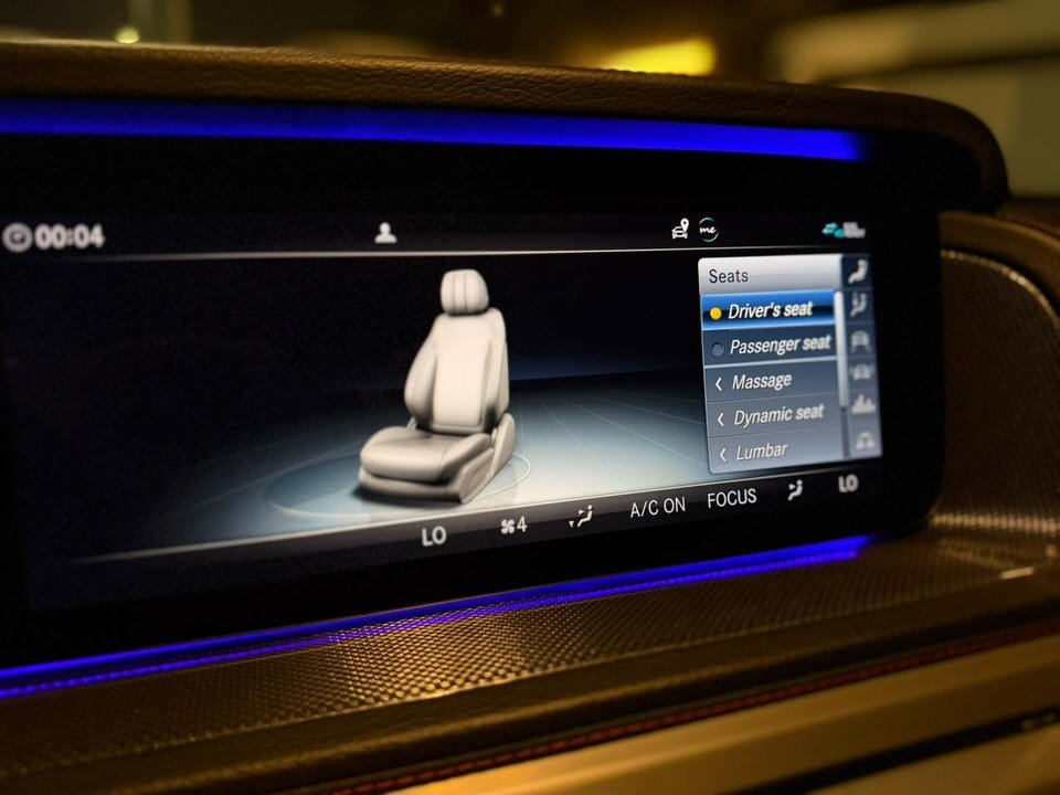 Car dashboard with a large screen in the center. The screen displays a 3D model of a person sitting in a car seat. The