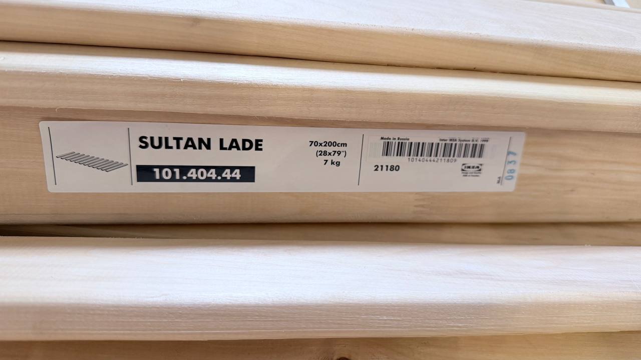 Stack of wooden planks with a label on them. The label reads "SULTAN LADE 101.404.44" and has a barcode and barcode barcode