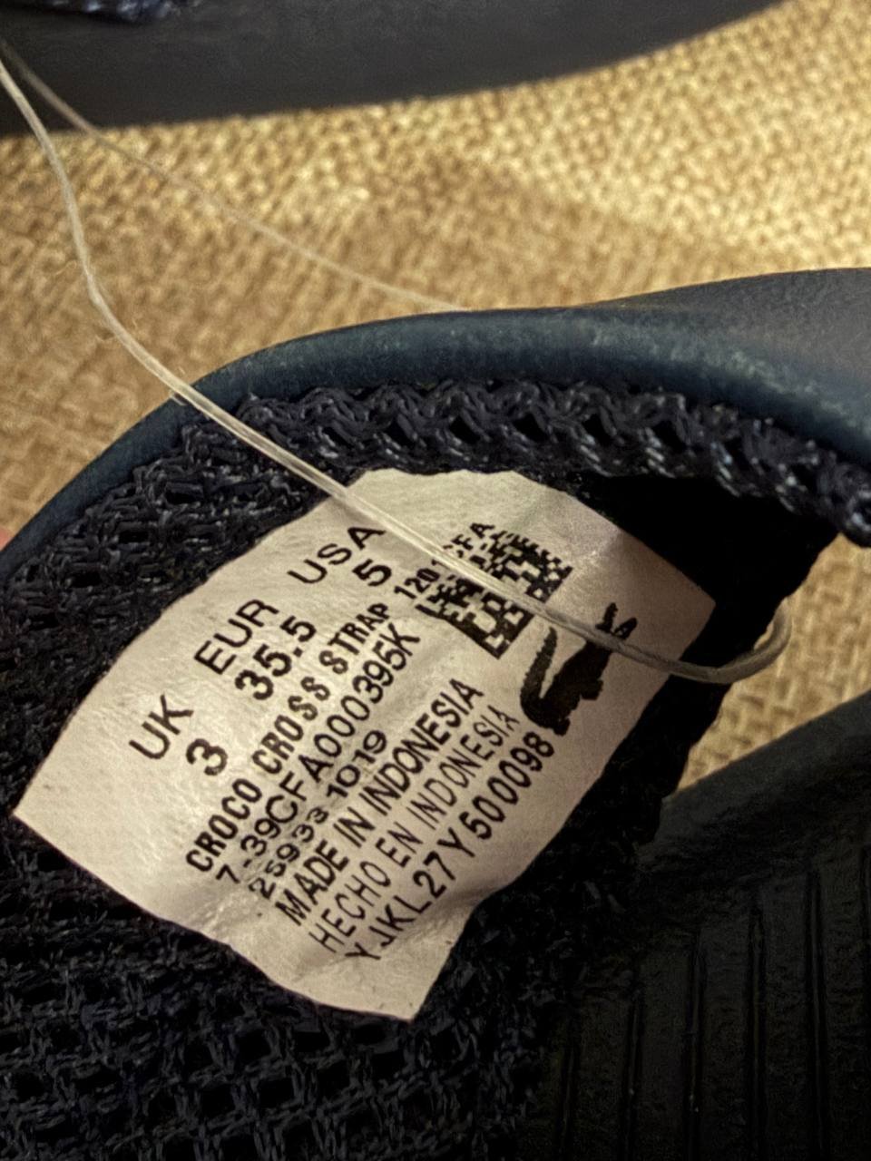Close-up of a label on the sole of a shoe. The label is white with black text and has a barcode and a QR code printed on it.