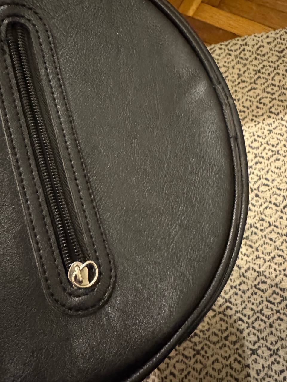 Close-up of a black leather pouch with a zipper. The pouch appears to be made of high-quality leather and has a smooth