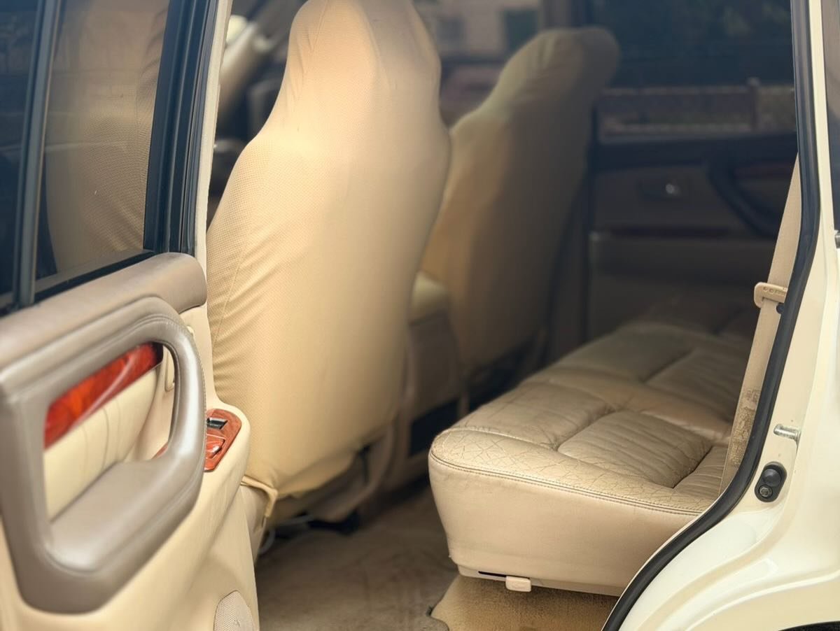 Interior of a car, specifically the back seat. The car appears to be a beige color and has a leather-like texture. The seat