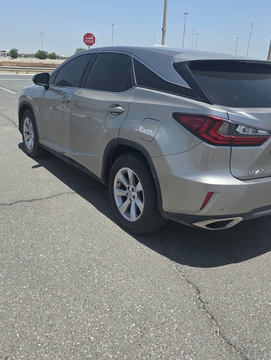 Silver Lexus SUV parked in an empty parking lot. The car is facing towards the left side of the image and is positioned at