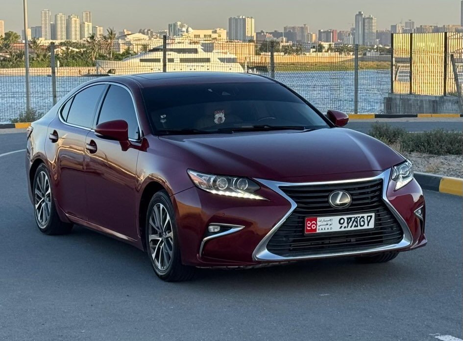 Red Lexus ES 350 car parked on the side of a road. The car is facing towards the left side of the image and is positioned at