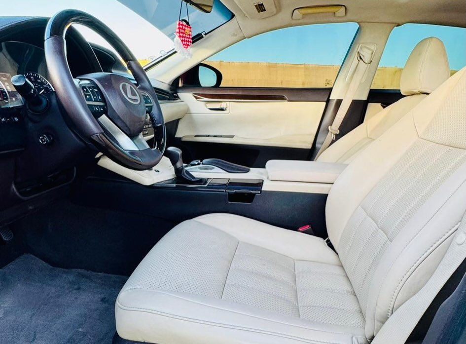 Interior of a car, specifically the driver's seat and the dashboard. The car appears to be a Lexus, as the logo of the car
