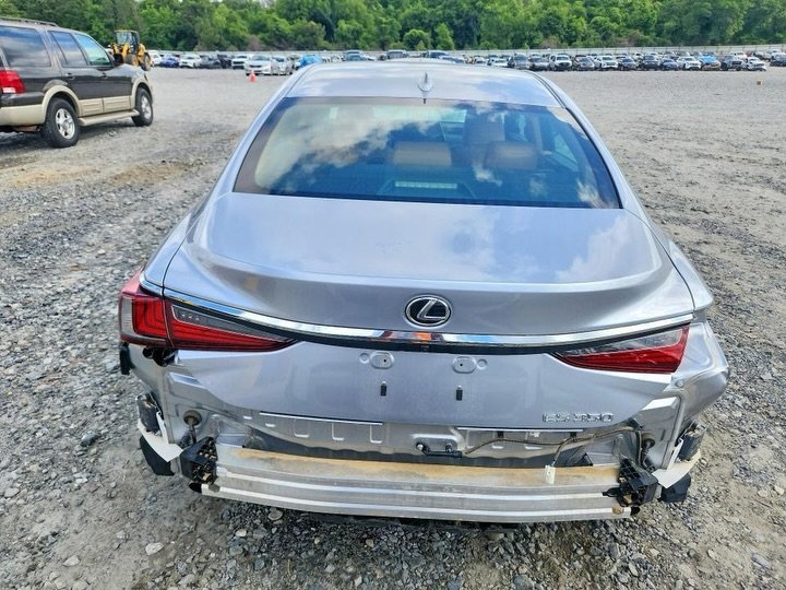 Rear view of a silver Lexus car. The car is parked in a lot with other cars visible in the background. The rear bumper is