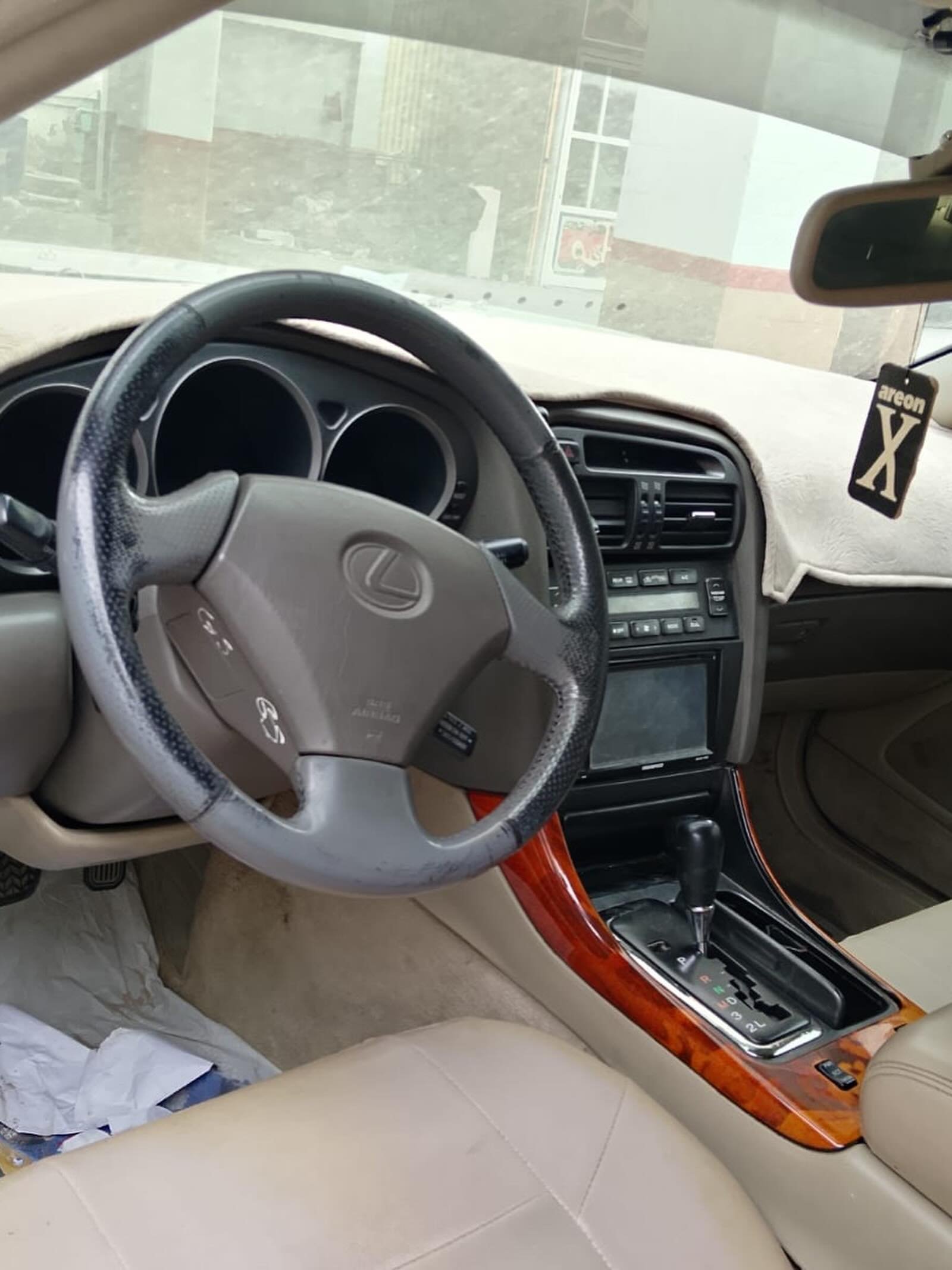 Interior of a car, specifically the driver's seat. The car appears to be a Lexus, as the logo on the steering wheel is