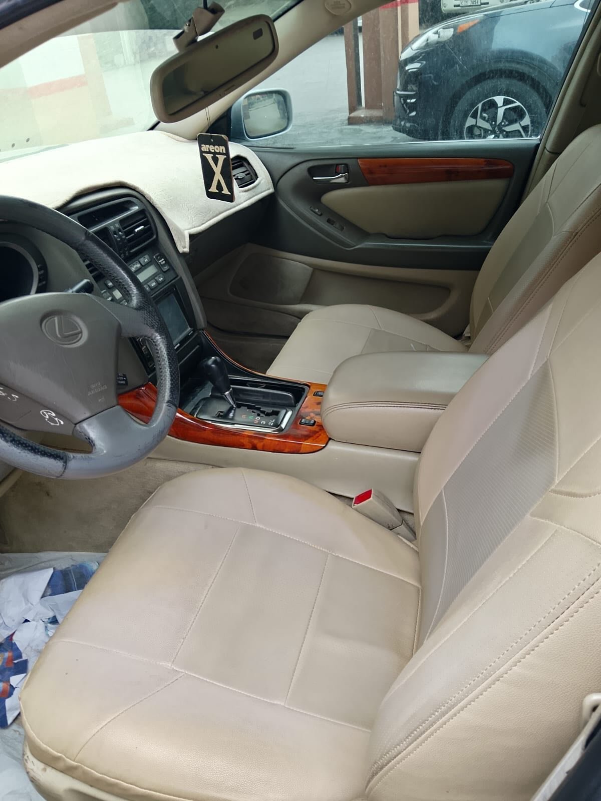 Interior of a car, specifically the back seat. The seat is beige in color and appears to be made of leather. The back seat