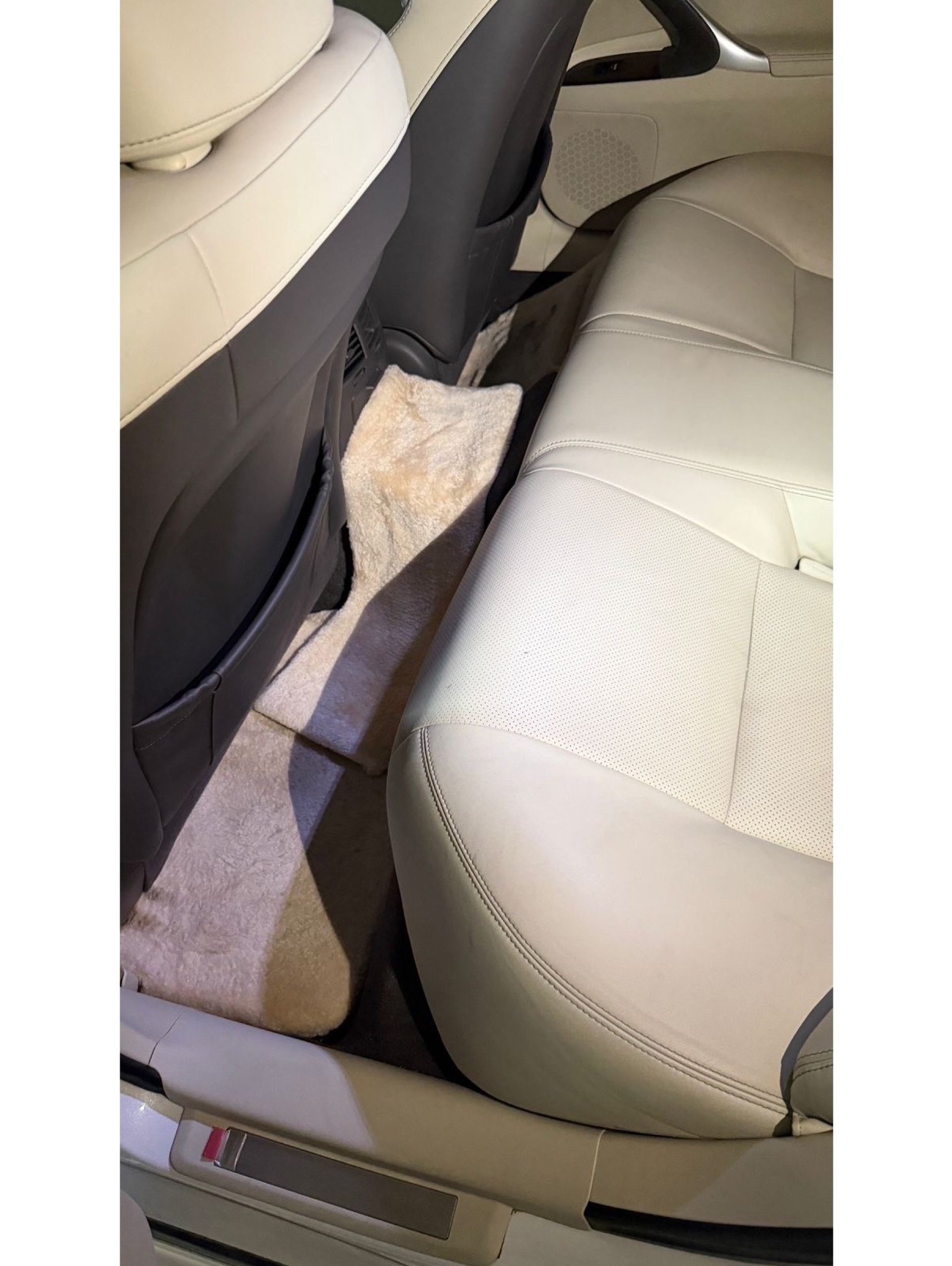 Interior of a car, specifically the back seat. The seat is beige in color and appears to be made of leather. The back seat