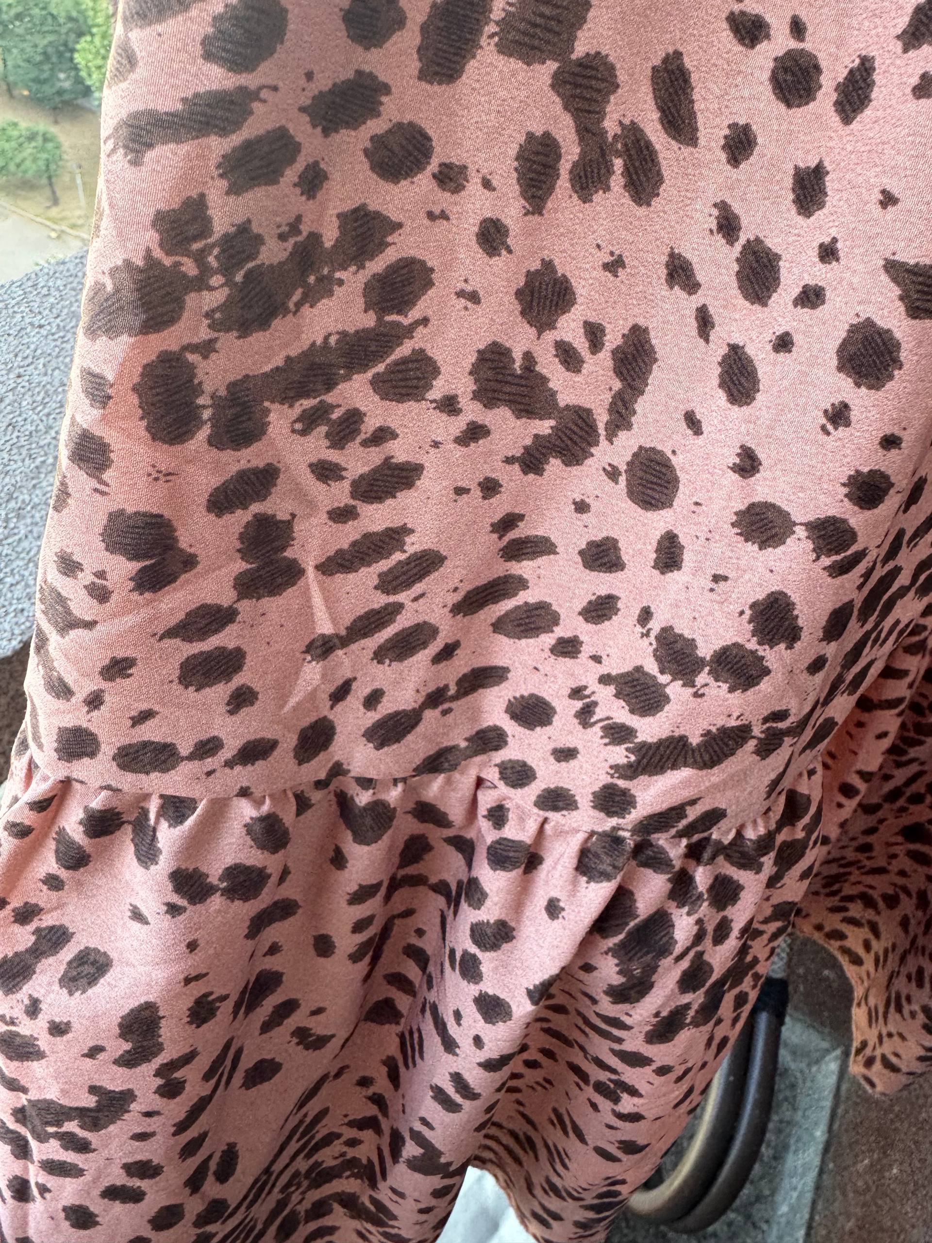 Close-up of a pink fabric with a leopard print pattern. The fabric appears to be made of a soft, lightweight fabric and has