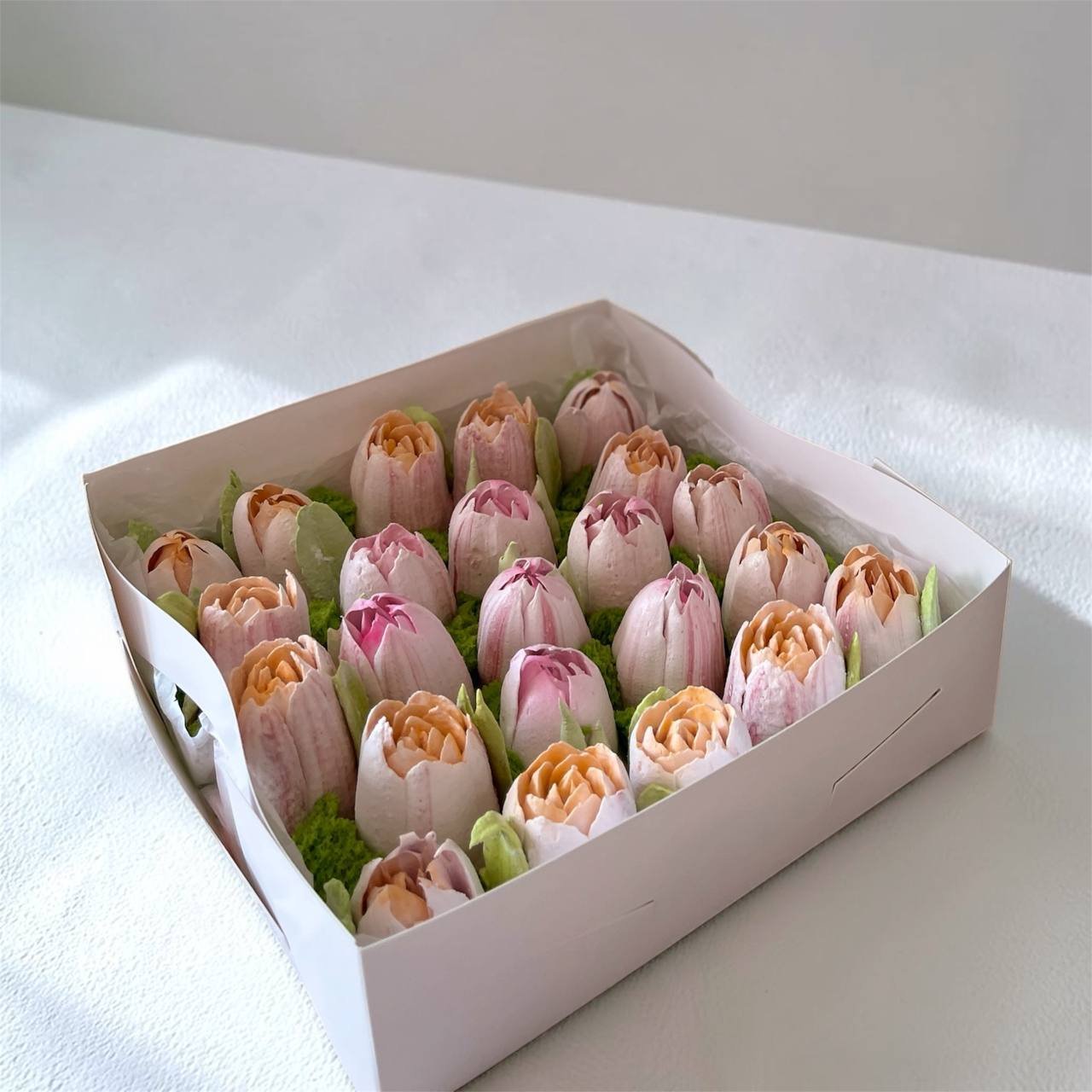 White rectangular box filled with small pink and orange flowers. The flowers are arranged in a neat and orderly manner, with