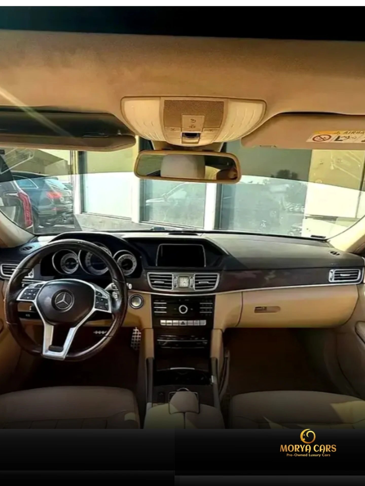 Interior of a car, specifically the driver's seat and dashboard. The car appears to be a Mercedes-Benz, as indicated by the