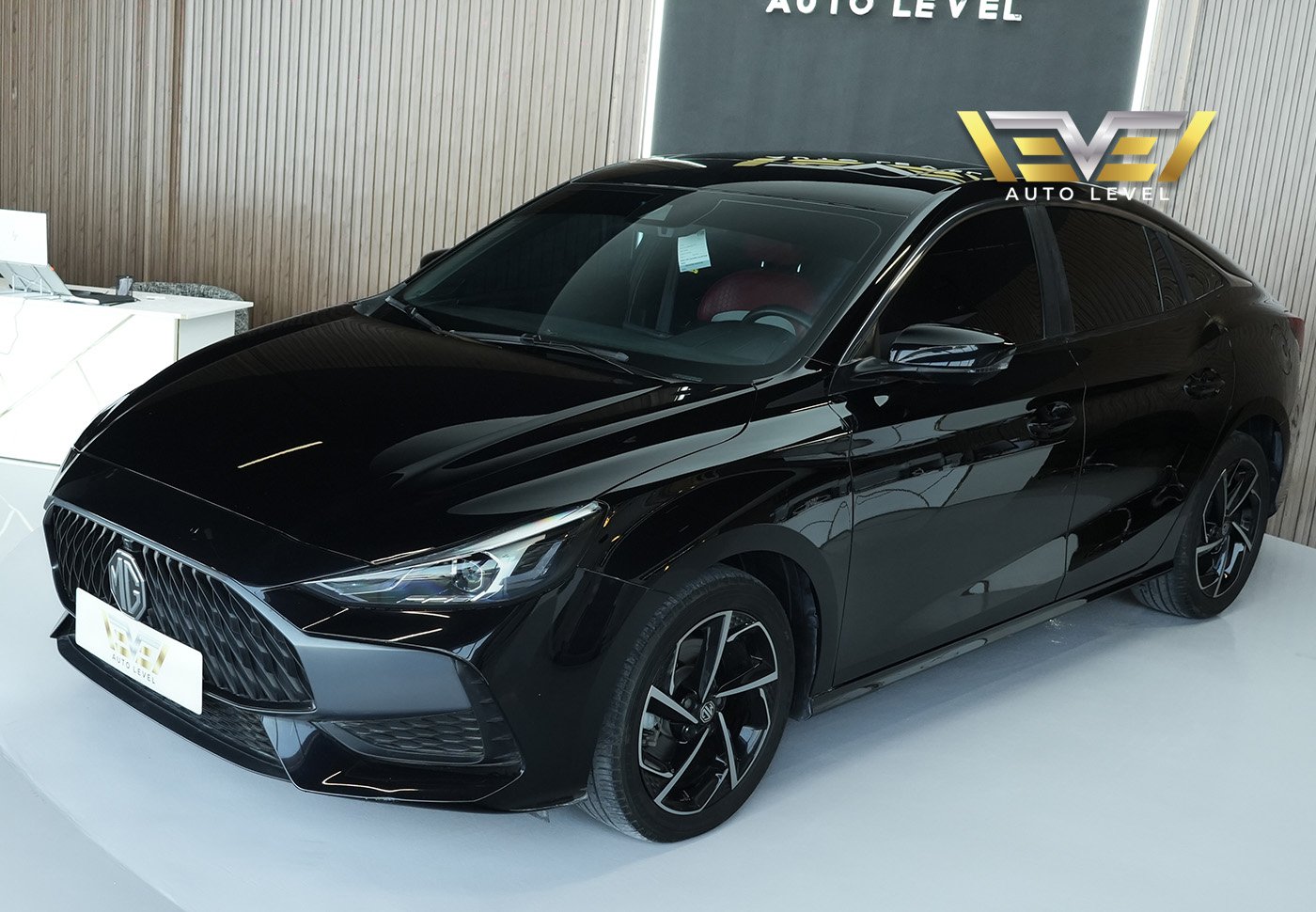 Black car on display at an auto show. The car is a sedan with a sleek and modern design. It has a large front grille with