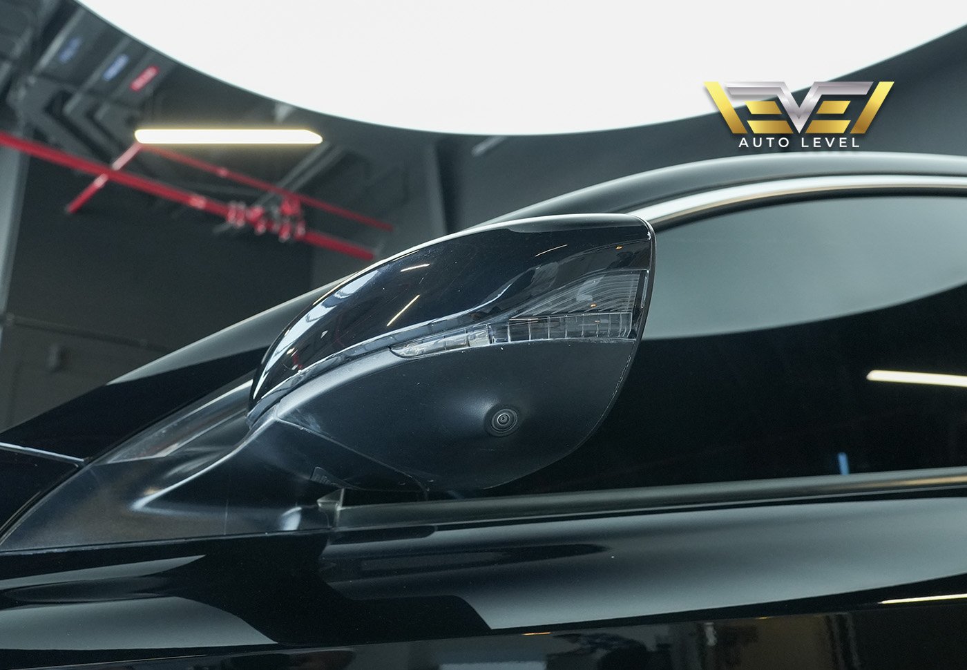 Side view mirror of a black car. The mirror is round and has a sleek design with a glossy finish. It is attached to the side