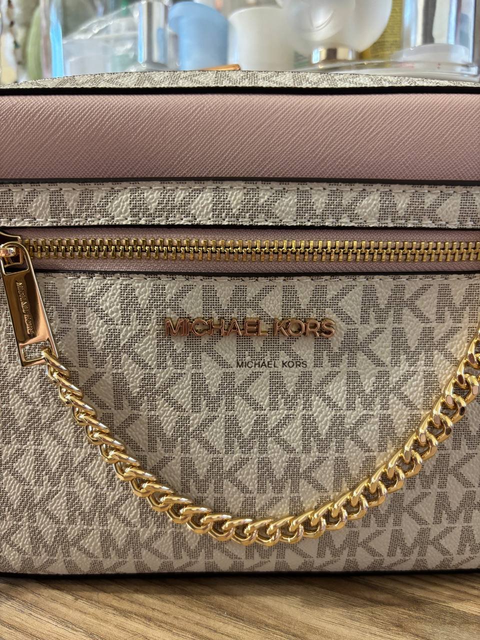 Michael Kors handbag with a gold chain strap. The bag is made of a beige-colored fabric with a geometric pattern. The top of