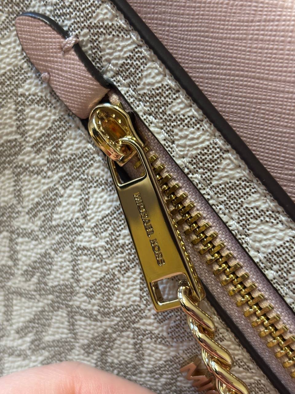 Close-up of a zipper with a gold-colored metal zipper puller attached to it. The zipper is open and the zipper is resting on