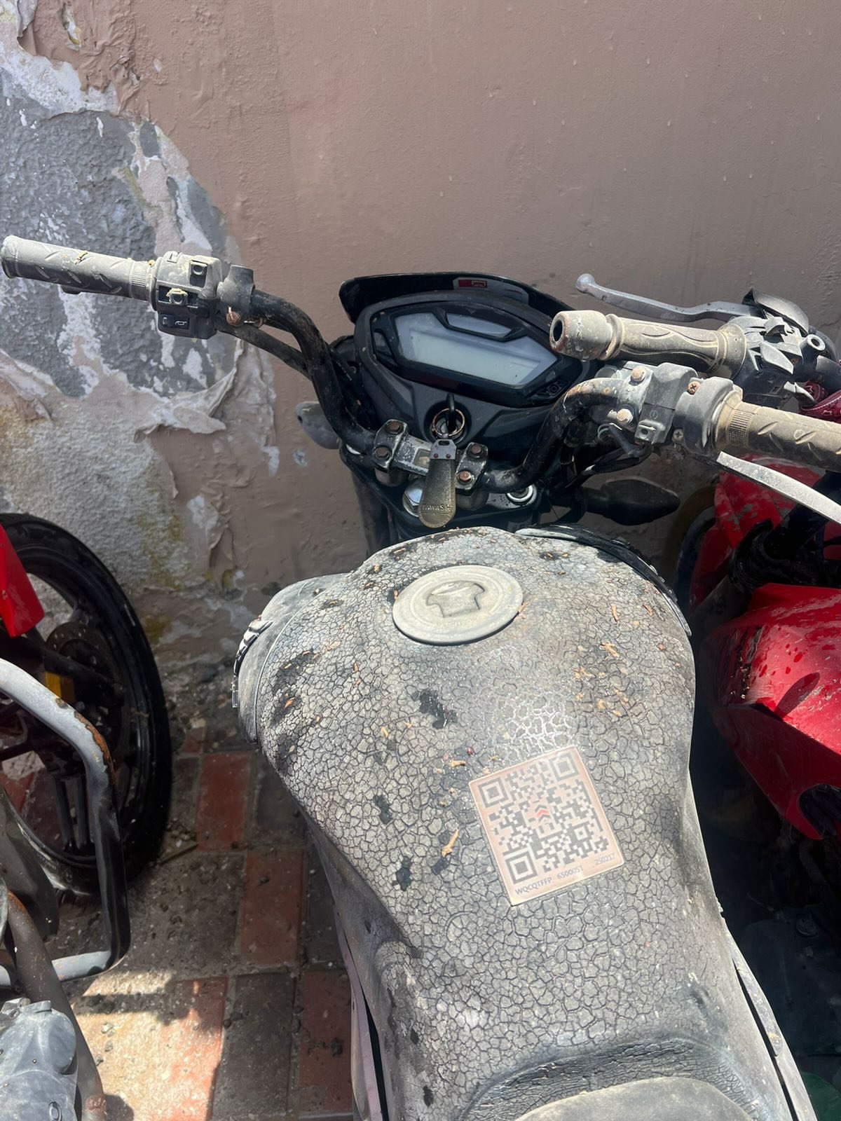 Handlebars of a motorcycle. The handlebars are black and have a digital display on them. The motorcycle is parked in front
