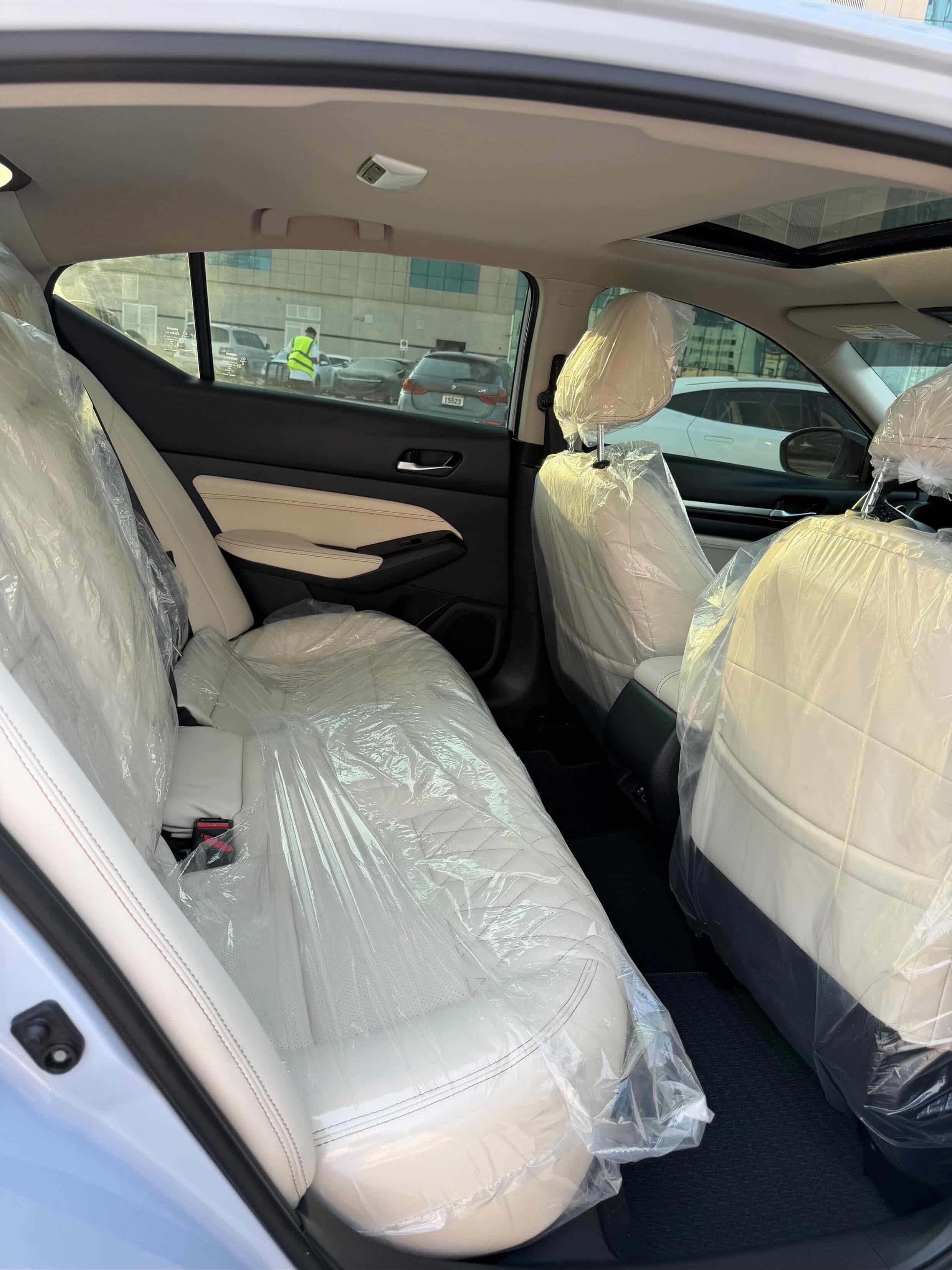 Interior of a car, specifically the back seats. The seats are covered with a transparent plastic wrap, which is likely to