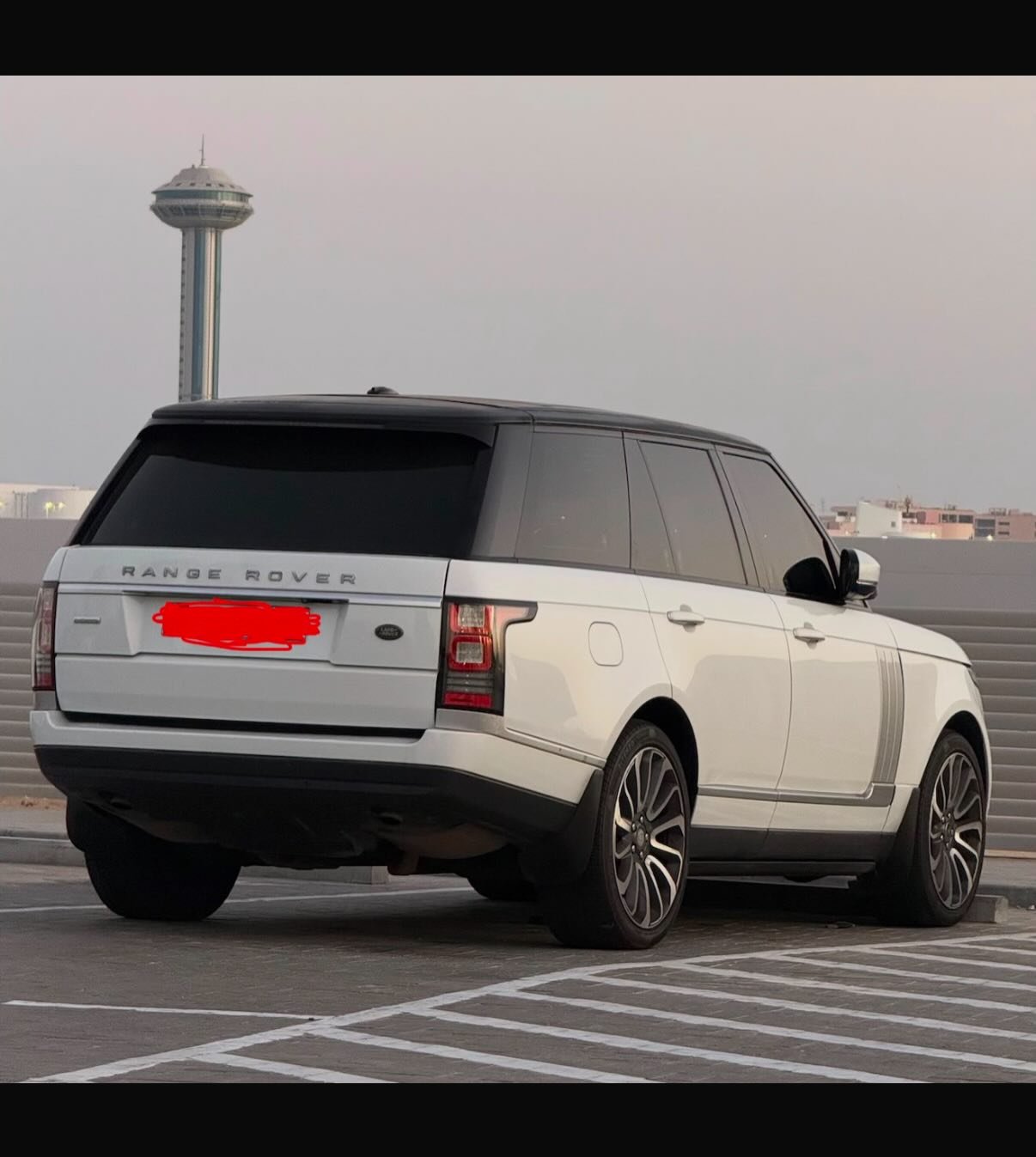 White Range Rover parked in a parking lot. The car is facing towards the left side of the image and is positioned in a way