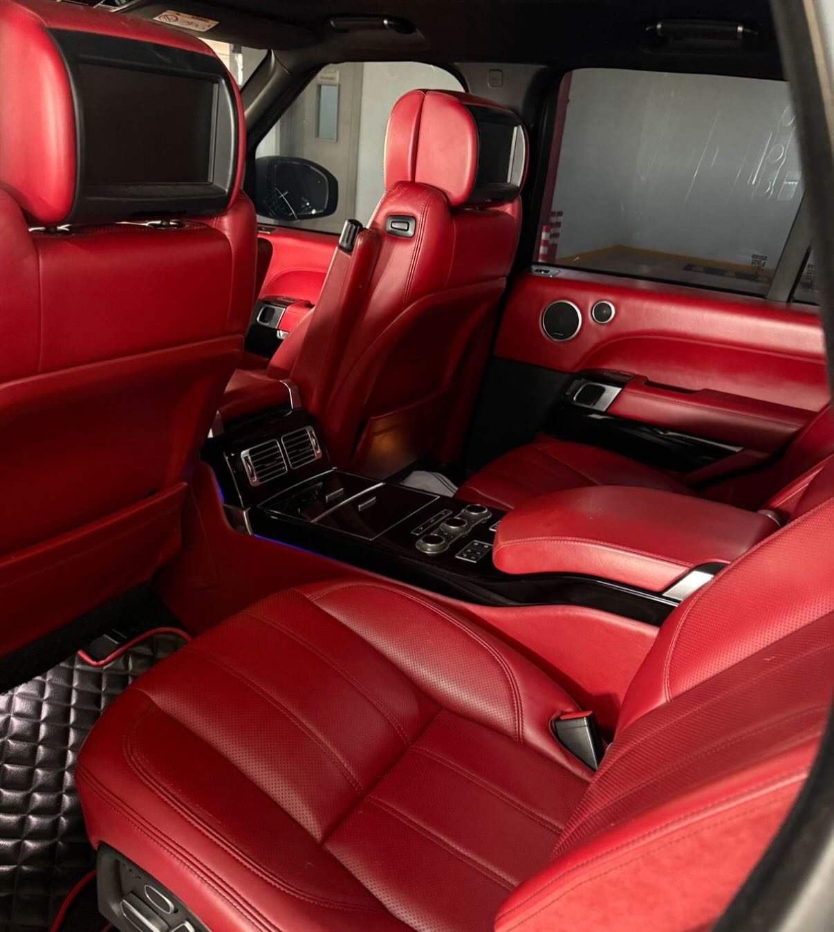 Interior of a luxury car, specifically the front seats. The seats are covered in red leather and have a sleek and modern