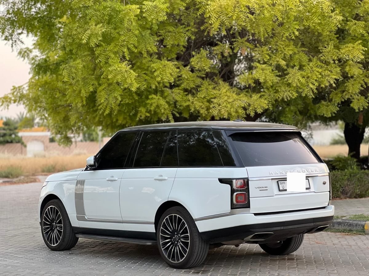 White Range Rover parked on a cobblestone street. The car is a luxury SUV with a sleek and modern design. It has a large