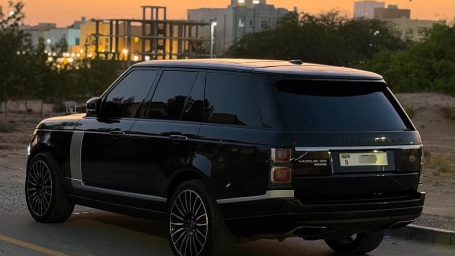 Black Range Rover parked on the side of a road at sunset. The car is facing towards the right side of the image and is