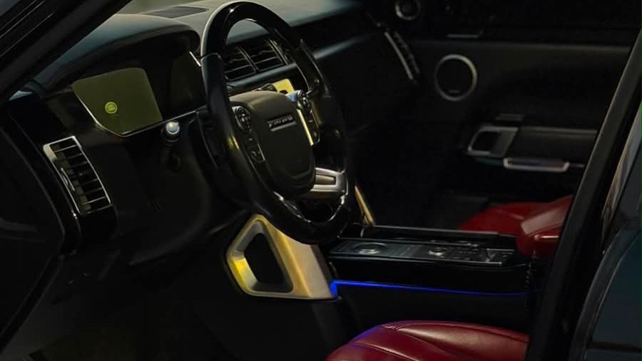 Interior of a car, specifically the driver's seat and dashboard. The car appears to be a luxury SUV, with a black leather