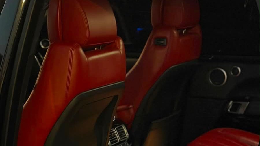 Interior of a car, specifically the front seats. The seats are upholstered in a deep red leather with a shiny finish. The