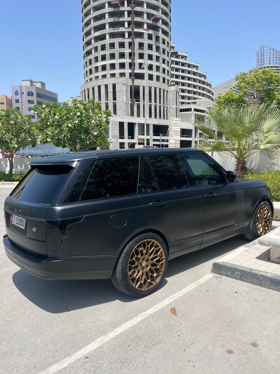 Black Range Rover parked on the side of a street. The car is a four-door SUV with a sleek and modern design. It has gold