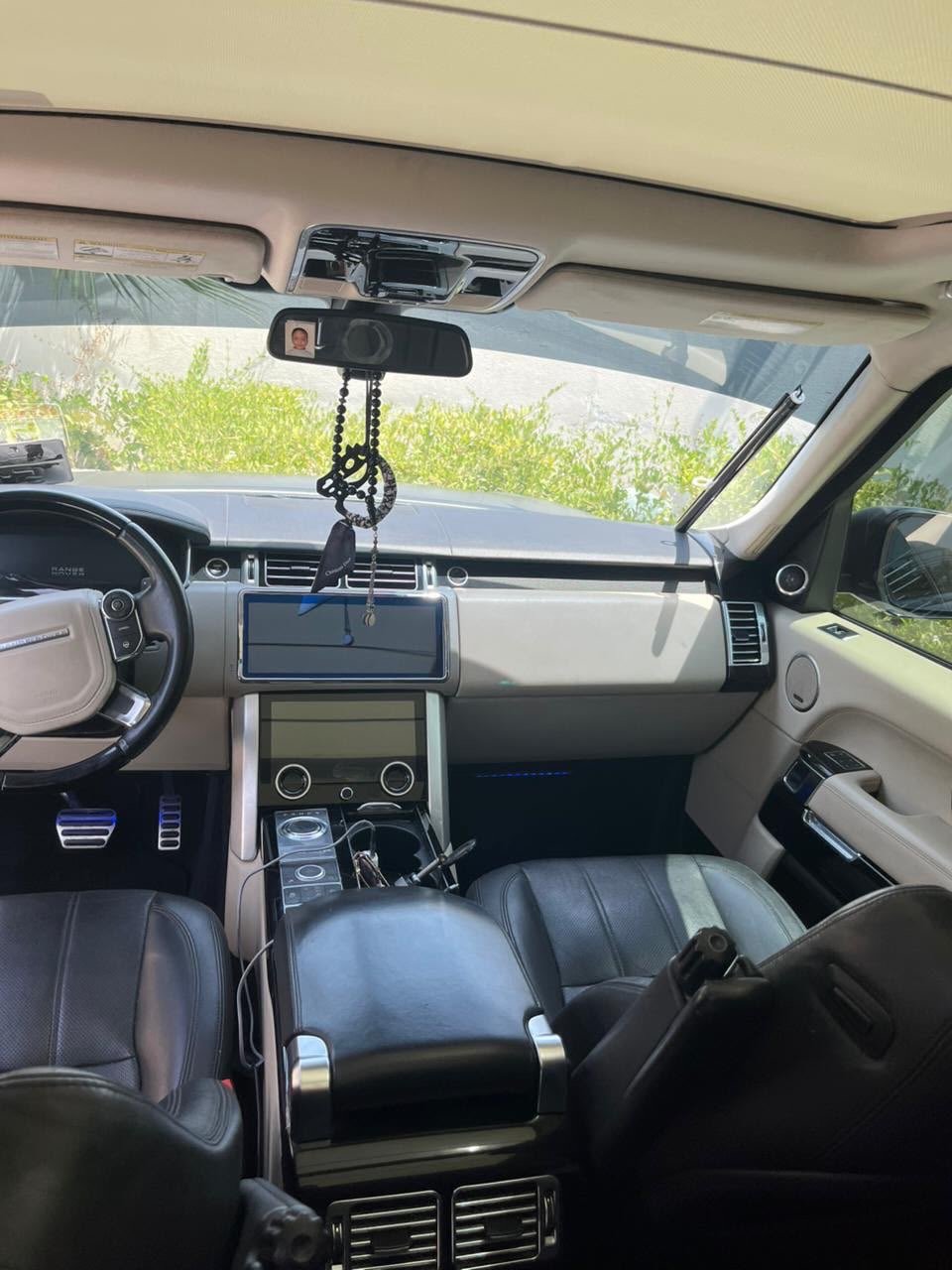 Interior of a car, specifically the driver's seat and dashboard. The car appears to be a luxury SUV, with a black leather